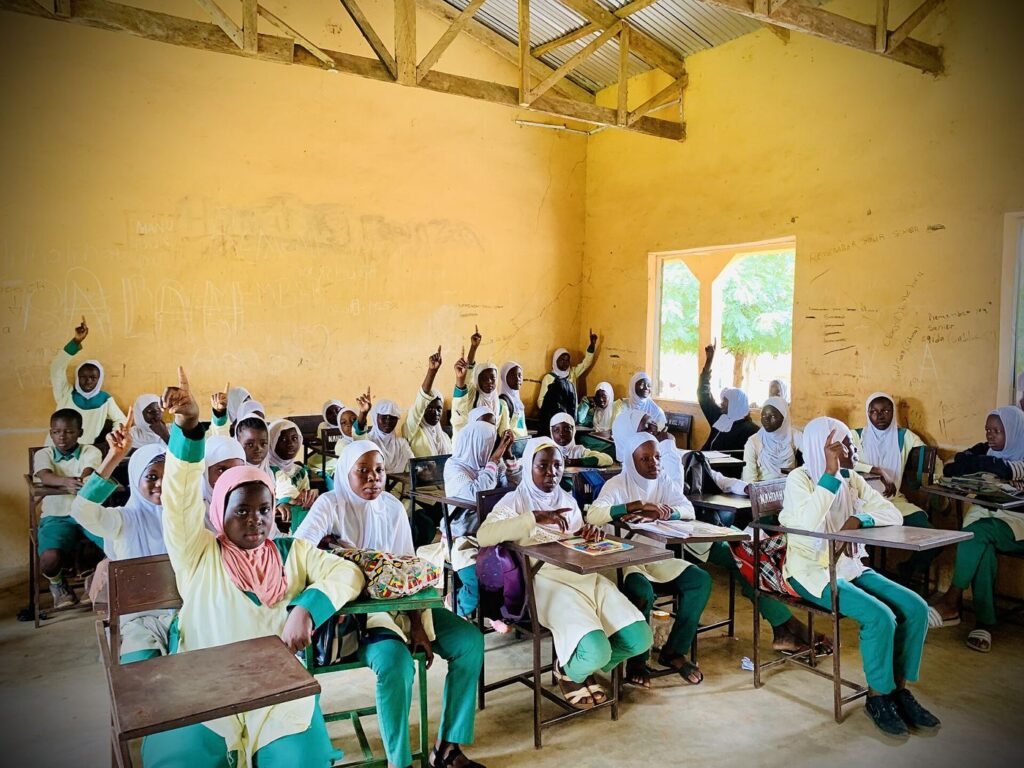 Students raise hands and ask questions during an interactive classroom learning session.
