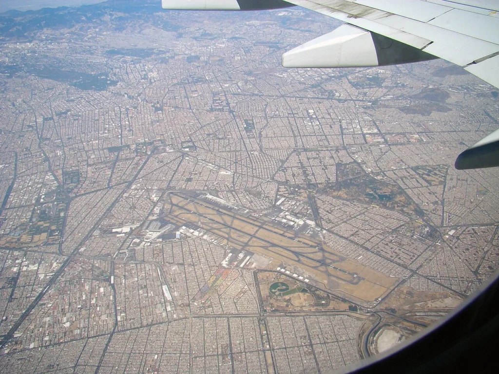 An aerial view over Mexico City, showing the airport and the city spreading out beyond it.